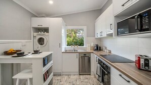 A modern kitchen with white cabinetry, a built-in washer, a dishwasher, and a microwave.