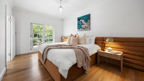 Ein Schlafzimmer mit einem Holzbett, einem Nachttisch, einer Lampe und einem Gemälde an der Wand.