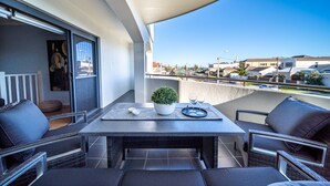 A balcony with a table, chairs, a potted plant, and a view of the neighborhood. - Higher Ground on Seaview - Rooftop Coastal Escape (West Beach)
