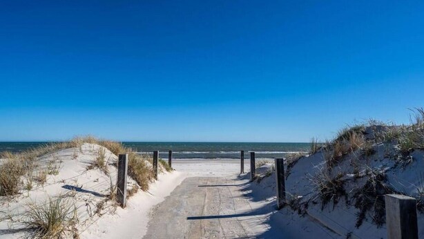 A sandy pathway leading to a beach with dunes and a clear blue sky. - Higher Ground on Seaview - Rooftop Coastal Escape (West Beach)