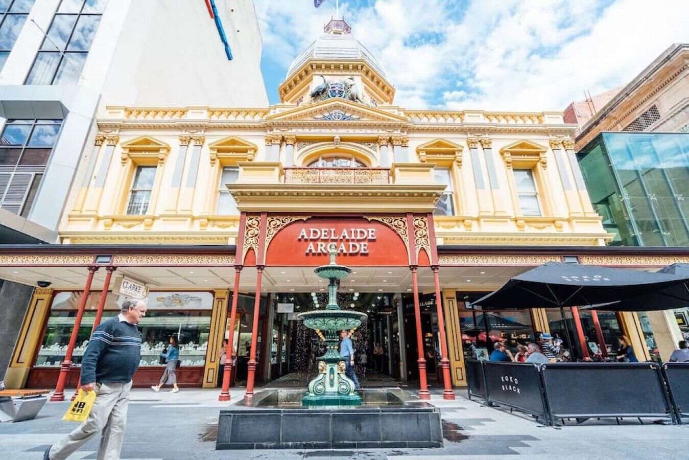 Adelaide Arcade with a central fountain, ornate architecture, and a sign above the entrance.