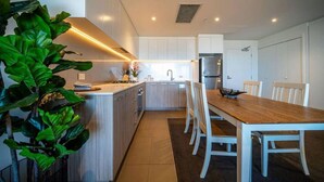 Une cuisine moderne avec des meubles blancs, une table à manger en bois et des chaises.