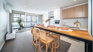 Une cuisine moderne dotée d’un long comptoir en bois, d’armoires encastrées et d’une grande fenêtre offrant une vue sur la ville.