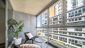 Un balcon avec une plante en pot, deux chaises et une petite table.
