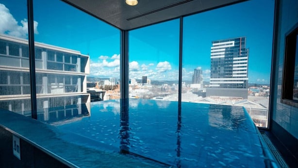 Une piscine intérieure moderne avec vue sur la ville, de grandes fenêtres et un design épuré et contemporain.