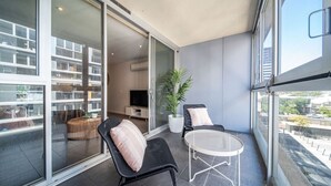 Un balcon avec un espace salon, un pot de fleurs et une vue sur le paysage urbain.