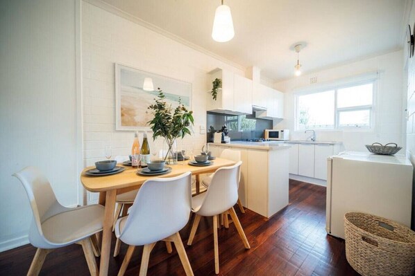 A modern kitchen with white cabinetry, a wooden dining table, and a central island.