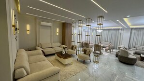 A modern living room with a sectional sofa, armchairs, a coffee table, and decorative lighting. - villa with garden in continental COMP (Sheikh Zayed City)