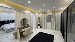 A modern bedroom with a bed, a vanity with a mirror, a desk, and a large window with curtains. - villa with garden in continental COMP (Sheikh Zayed City)