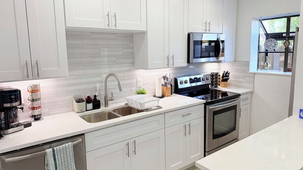 A modern kitchen with white cabinetry, stainless steel appliances, and a built-in oven. - Arlington Entertainment District Home Orange Door (Arlington)