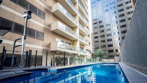 A modern building with a swimming pool, balconies, and a clear sky. - Serene on Grenfell - A Vibrant City Stay (Adelaide)