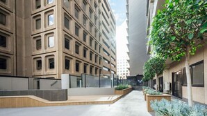A modern urban courtyard with a central pathway, surrounded by high-rise buildings and greenery. - Serene on Grenfell - A Vibrant City Stay (Adelaide)