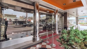 A hotel entrance with large glass doors, metal pillars, and a red carpet leading inside. - FORTUNE HOTEL (Xinyi)