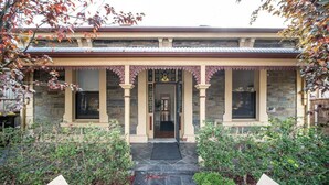 A traditional building with a stone facade, a tiled roof, and a symmetrical entrance with decorative columns. - Irma`s Place—A Historic Garden Cottage (Adelaide)