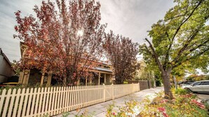 A residential house with a white picket fence, a driveway, and a garden with various plants and flowers. - Irma`s Place—A Historic Garden Cottage (Adelaide)