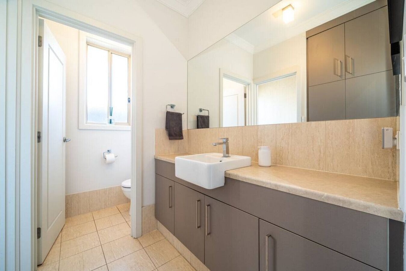 A modern bathroom with a sink, mirror, and cabinets.