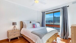 Une chambre à coucher avec un lit en bois, une table de chevet, une lampe et une fenêtre avec des rideaux.