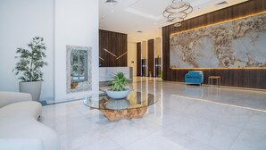 Un hall d’entrée moderne avec un comptoir de réception en marbre, une grande carte murale et un fauteuil bleu.