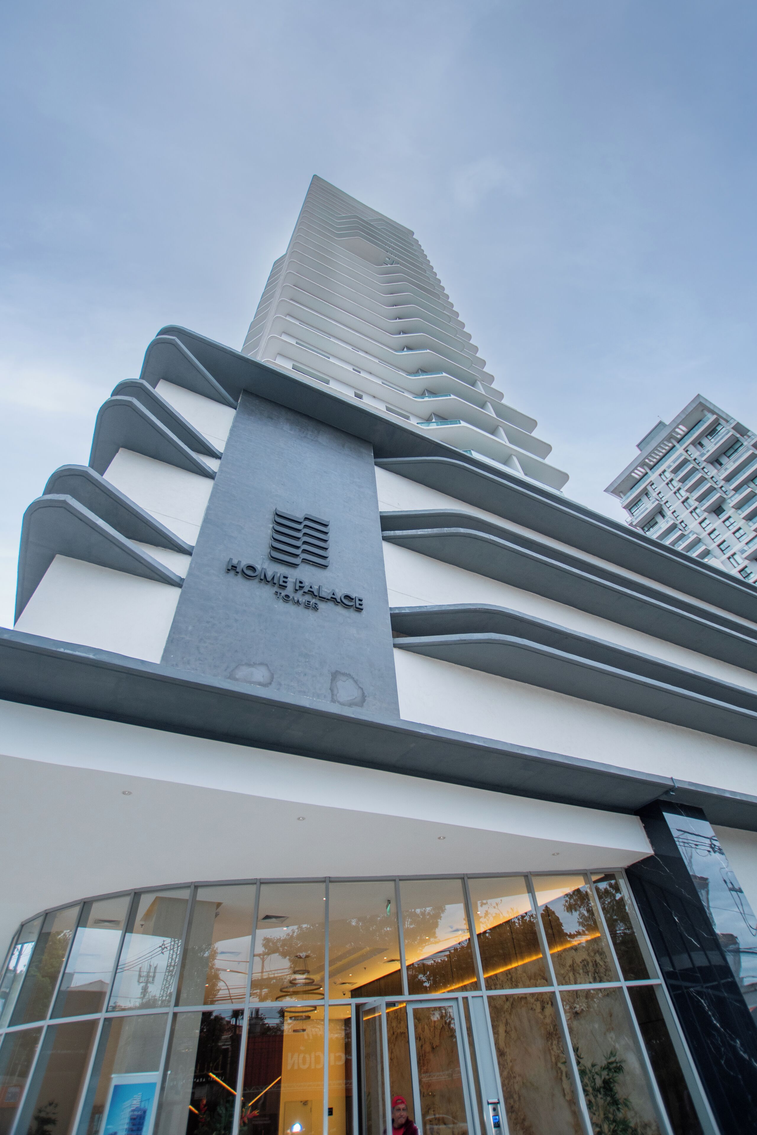 Un edificio moderno con una estructura vertical destacada identificada con el letrero 'HOME PALACE TOWER'.
