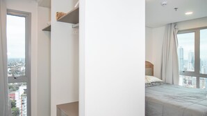 Ein Schlafzimmer mit einem Bett, einem Kleiderschrank, einem Fenster mit Blick auf die Stadt und einer Tür.
