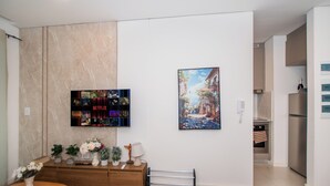 Un salon moderne avec un téléviseur à écran plat fixé au mur, une console en bois agrémentée d’objets décoratifs et un tableau encadré placé au-dessus.