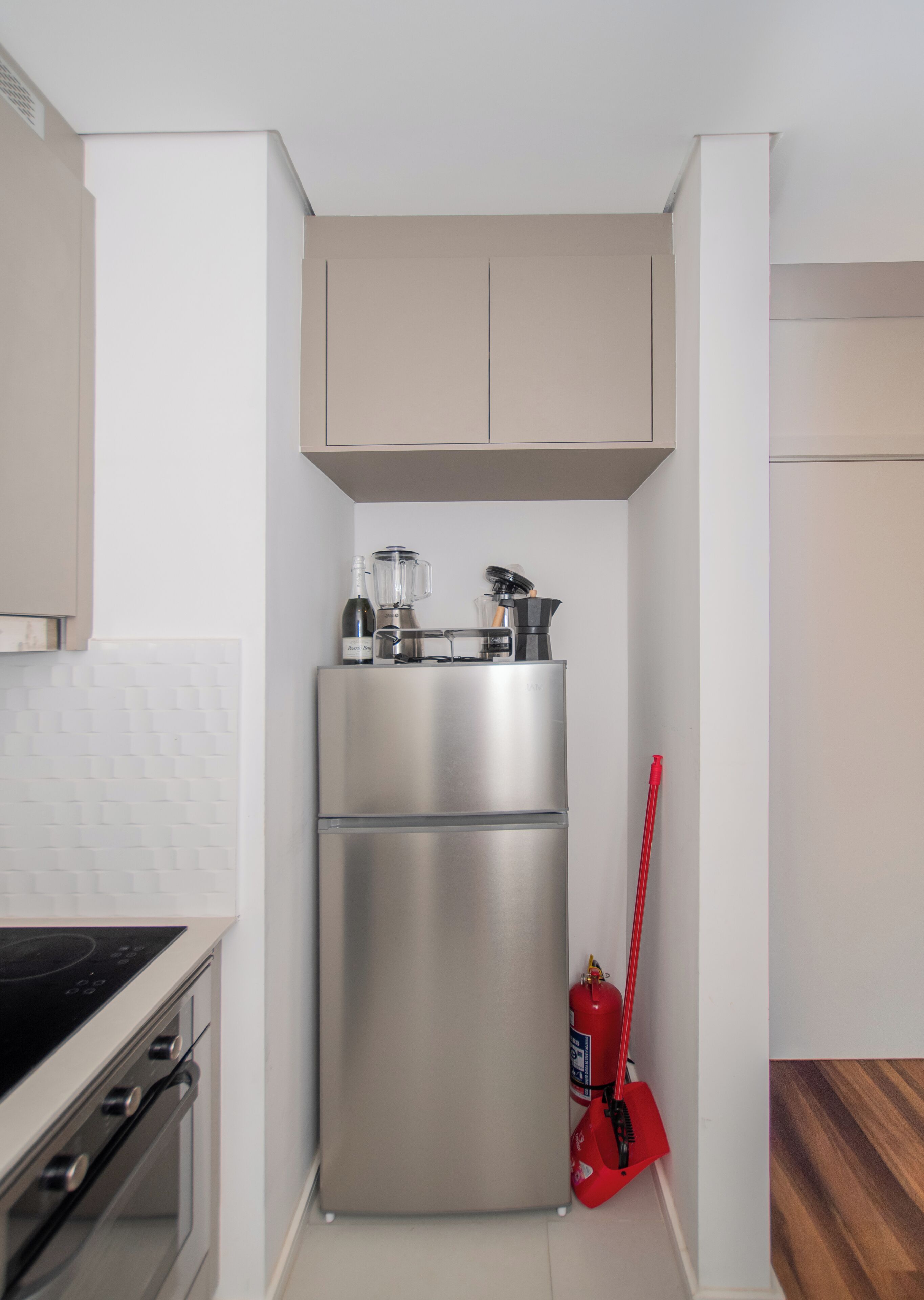 Eine kleine Küche mit einem Edelstahl-Kühlschrank, einem Mixer und einem roten Feuerlöscher.