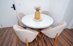 A round table with a pineapple centerpiece, surrounded by four chairs with wooden legs and fabric seats.