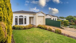 A single-story house with a garage, a well-maintained lawn, and a green fence.