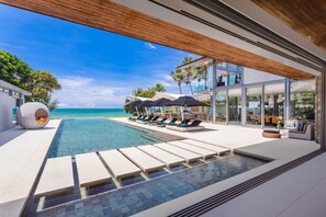 Un resort moderno con piscina, lettini e vista sull'oceano.