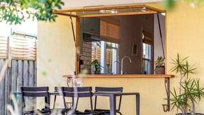 Un comedor con una mesa y sillas, un ventilador de techo y una ventana con vista a un muro de ladrillo.