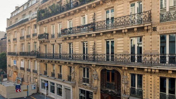 A multi-story building with ornate balconies, large windows, and a classical architectural style.