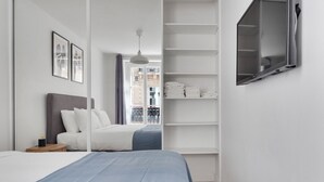 A bedroom with a bed, a bedside table, a wardrobe, and a TV mounted on the wall.