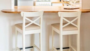 A kitchen with a wooden countertop, two white chairs, and a white stove.