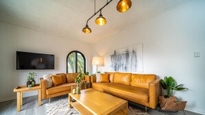 A living room with a sectional sofa, a coffee table, a TV, and a large window.