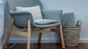 A corner room with a light blue armchair, a woven basket, and a view of the outdoors through a window.