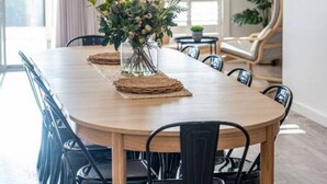 A dining area with a long wooden table, black chairs, and a centerpiece of flowers.