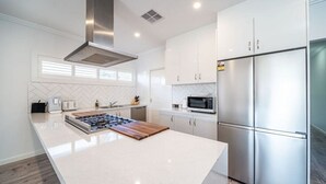 A modern kitchen with a central island, stainless steel appliances, and white cabinetry.