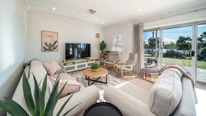 A modern living room with a sofa, chairs, a coffee table, and a TV.