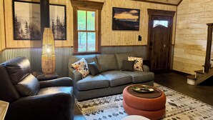 Ein gemütliches Wohnzimmer mit einem Ledersofa, einem gemusterten Teppich und einem Kamin.
