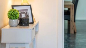 A small white table with a lamp, a framed photo, and a potted plant in a hotel lobby. - Escape to Adelaide Hills—Spacious Country Stay (Nairne)