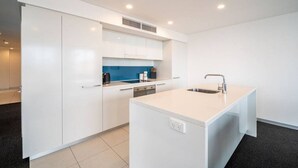 A modern kitchen with white cabinetry, a blue backsplash, and a central island with a sink.