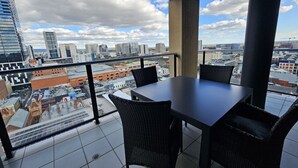A balcony with a table and chairs, offering a city view.