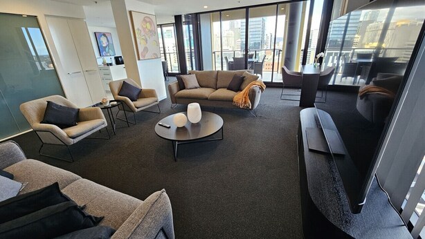 A modern living room with a sofa, armchairs, a coffee table, and a TV.