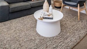 Un salon moderne avec un canapé gris, une table basse blanche et un fauteuil bleu.
