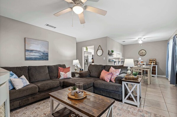 A living room with a sectional sofa, a coffee table, and a ceiling fan.