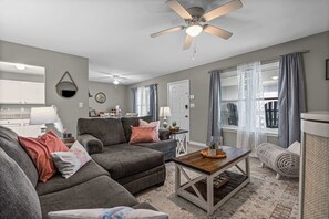A living room with a sofa, coffee table, and a ceiling fan.