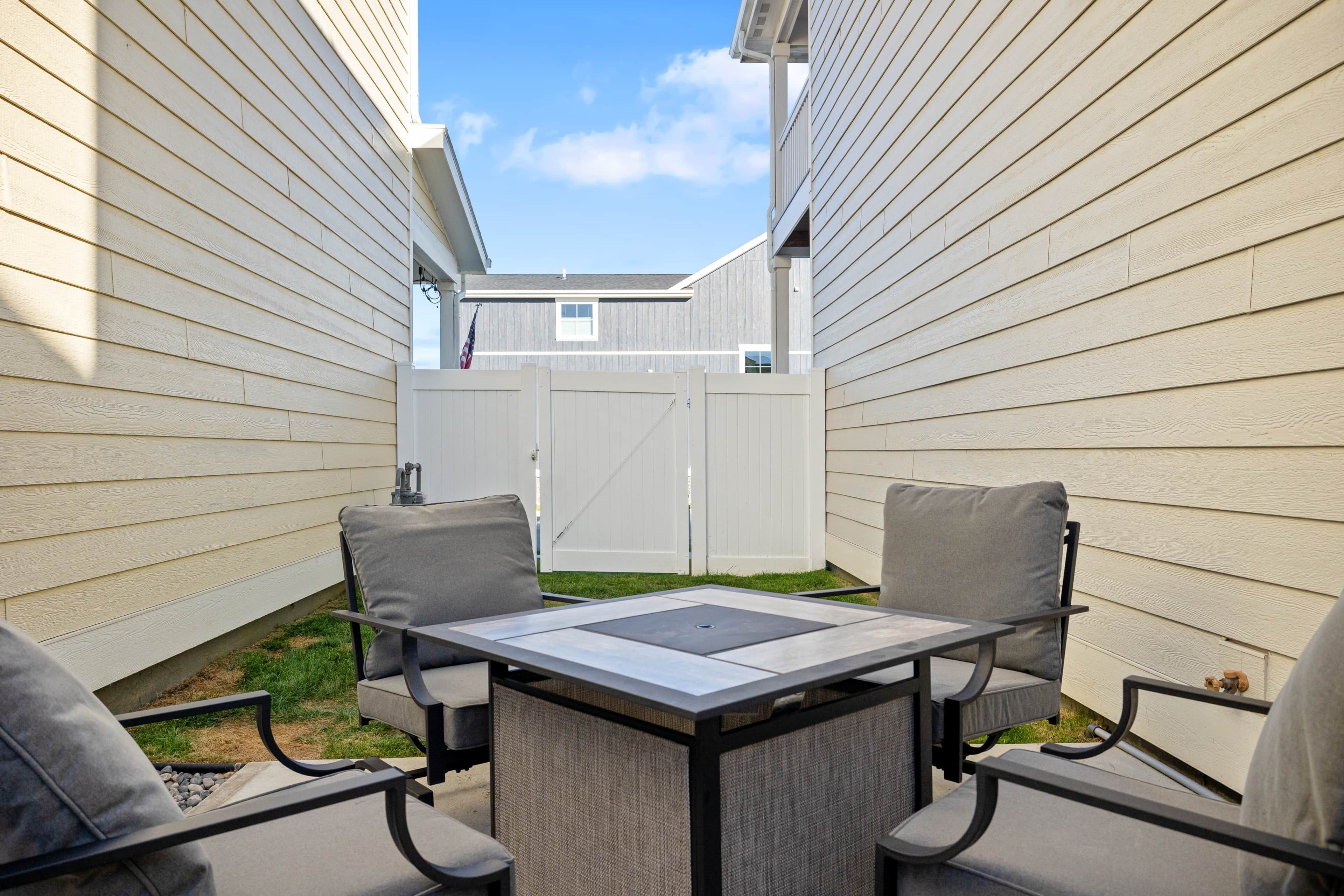 A patio with a table and chairs, surrounded by white siding walls.