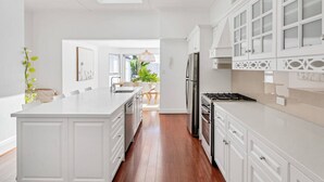 A modern kitchen with white cabinetry, a central island, and a skylight. - Villa 1 @ THE OSLO on Broadway with Pool (Glenelg South)