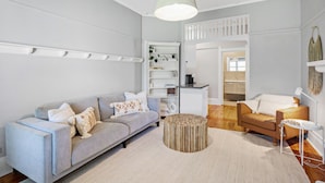 Una sala de estar moderna con un sofá gris, una mesa de centro redonda de madera y una lámpara colgante.