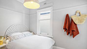 A bedroom with a bed, a window, a hanging basket, and a lamp.